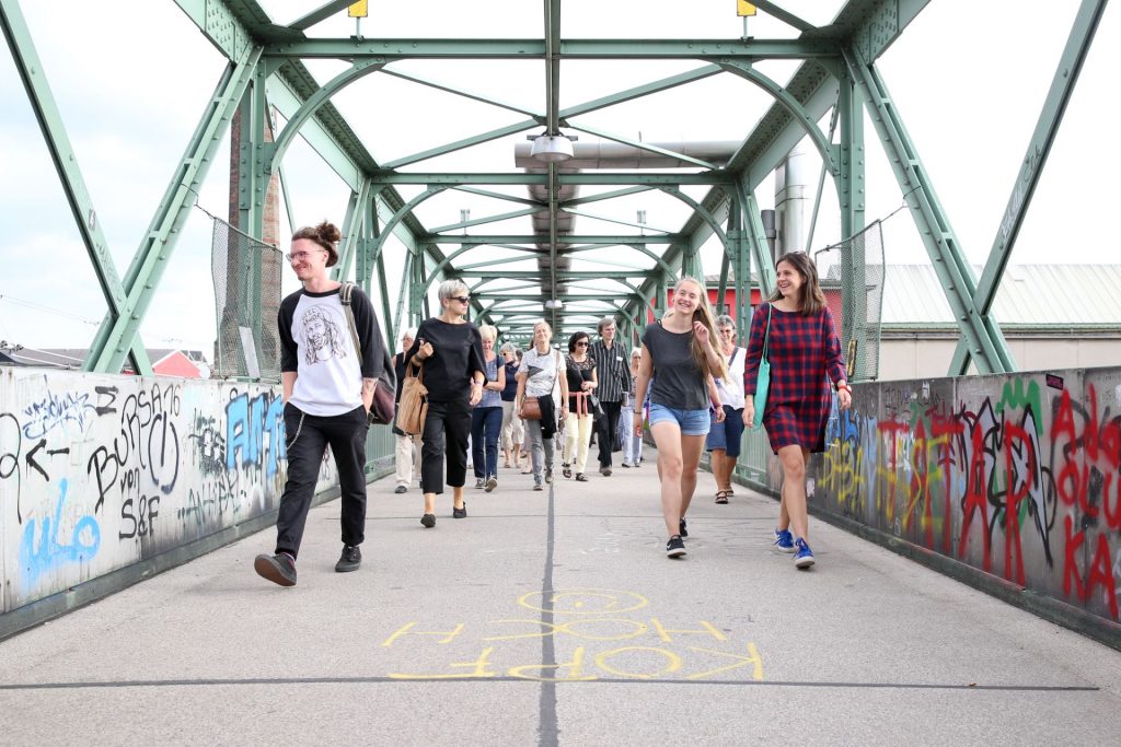 Eine Gruppe FußgängerInnen geht über die Brücke über den Westbahnhof.