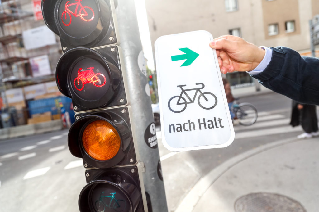 Eine Fahrradampel und ein Zusatzschild, dass Radfahrenden anzeigt, dass sie auch bei Rot rechts abbiegen dürfen.