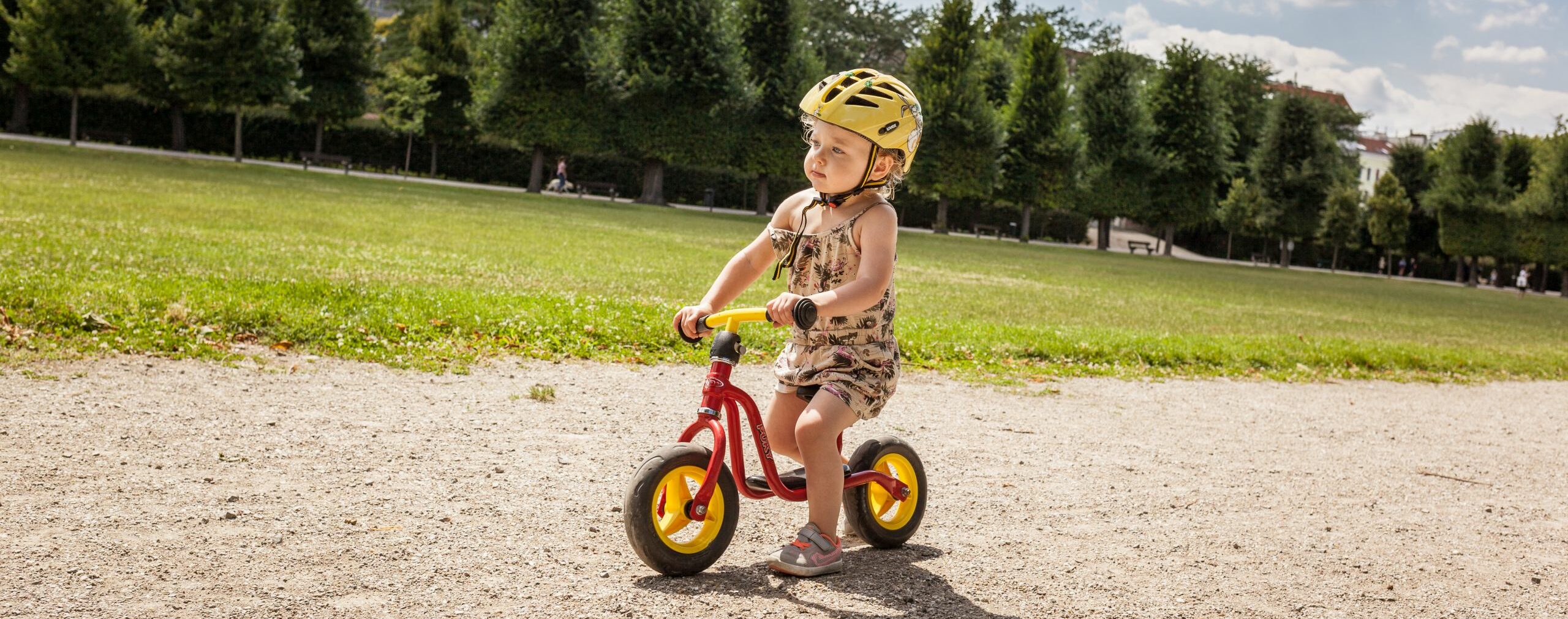 Kindergartenkind fährt mit Laufrad über einen schotter-weg