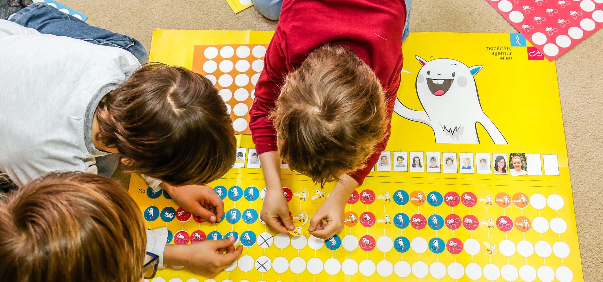 Kinder kleben bunte runde Sticker auf ein Plakat